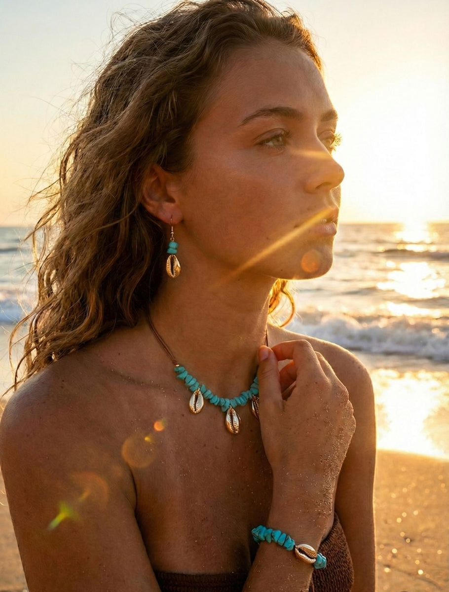 Woman on a beach with turquoise  and golden cowries jewelry against a sunset background
