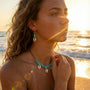 Woman on a beach with turquoise  and golden cowries jewelry against a sunset background