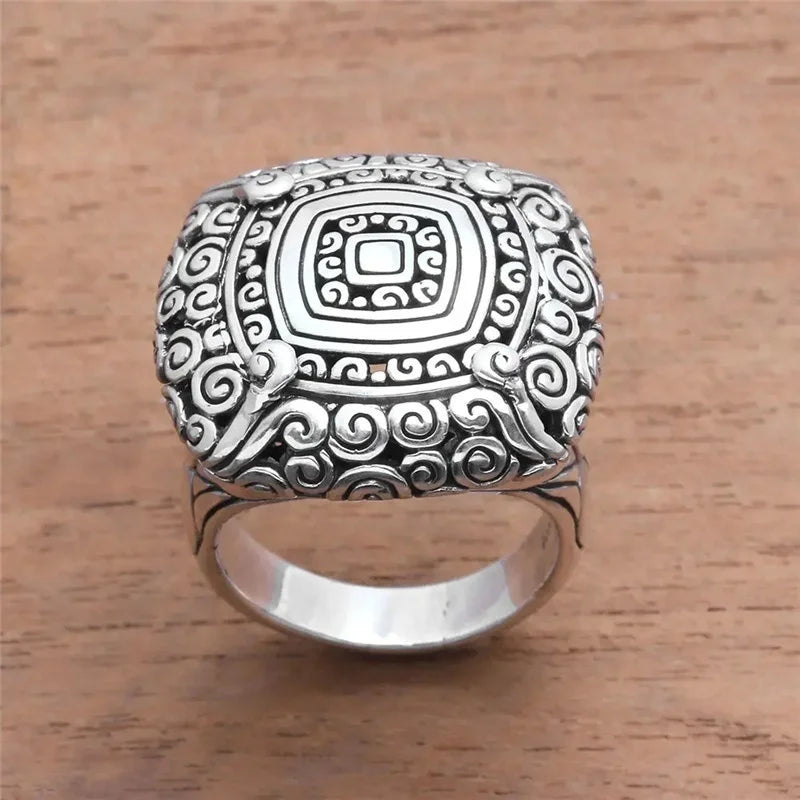 Silver ring with intricate design on a wooden surface