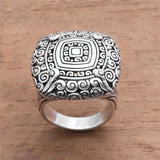 Silver ring with intricate design on a wooden surface