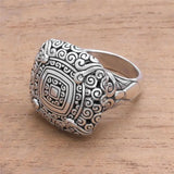Silver ring with intricate design on a wooden surface
