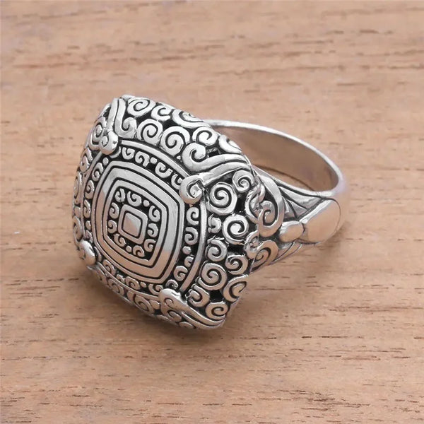 Silver ring with intricate design on a wooden surface