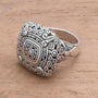 Silver ring with intricate design on a wooden surface