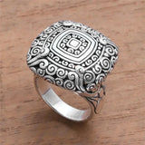 Silver ring with intricate design on a wooden surface