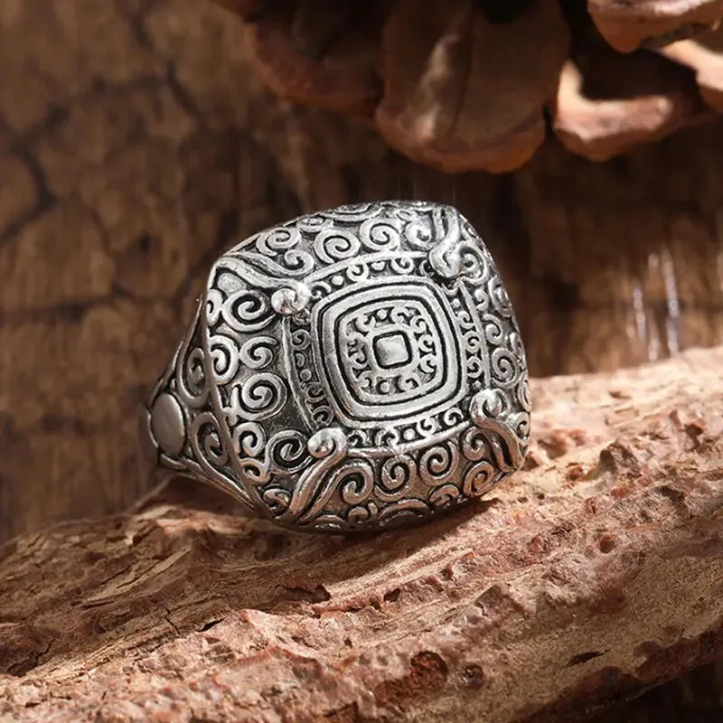 Silver ring with intricate design on a wooden surface