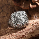 Silver ring with intricate design on a wooden surface