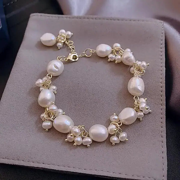Baroque pearl bracelet with gold accents displayed on grey suede, beach vibes aesthetic.