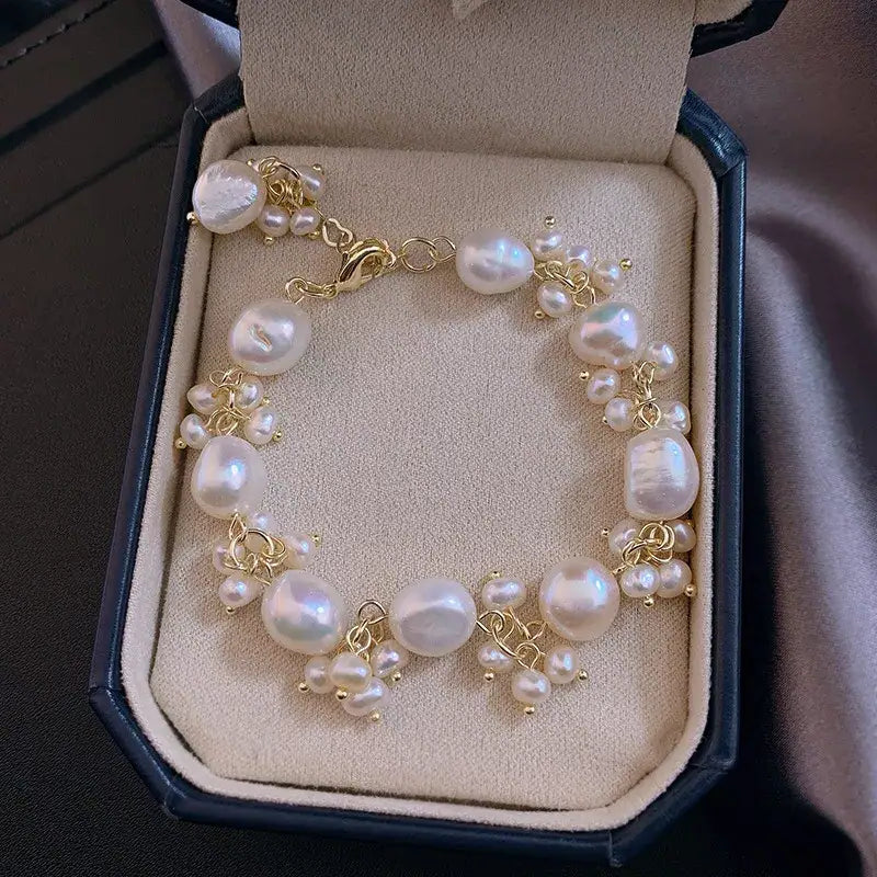 Pearl charm bracelet in jewelry box showing gold detailing and handcrafted details.