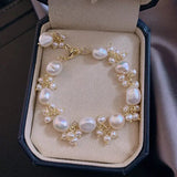 Pearl charm bracelet in jewelry box showing gold detailing and handcrafted details.