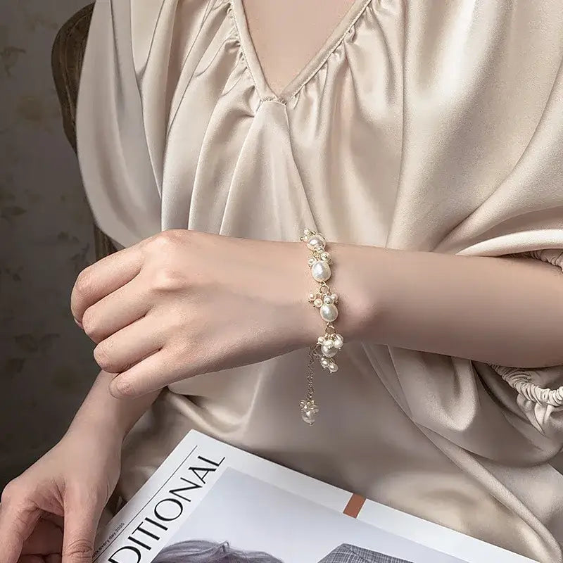 Elegant baroque pearl charm bracelet worn on wrist, soft bohemian chic style.