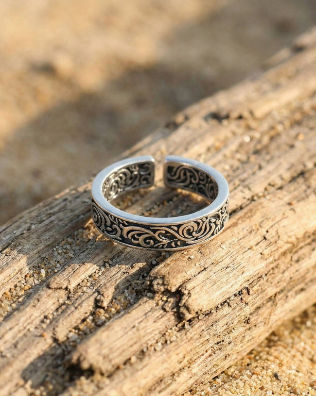 Silver ring with intricate designs on a wooden surface