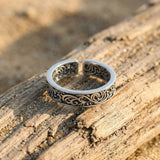 Silver ring with intricate designs on a wooden surface