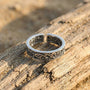 Silver ring with intricate designs on a wooden surface