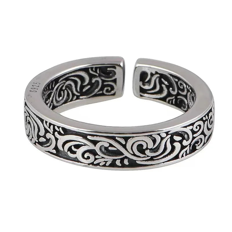 Silver toe ring with intricate black patterns on a white background