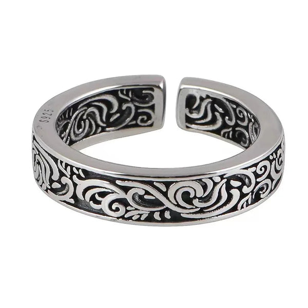 Silver toe ring with intricate black patterns on a white background