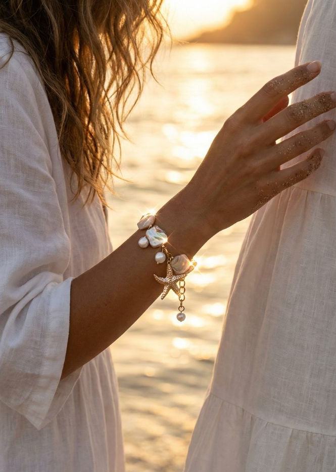 young woman wearing a golden starfish and shell bracelet with a sunset in the background