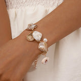 Pearl and shell bracelet on a wrist with a neutral background