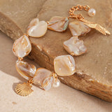 Bracelet with shell and pearl charms on a stone surface