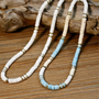 Natural shell necklaces in blue and white tones displayed on driftwood, tropical style jewelry
