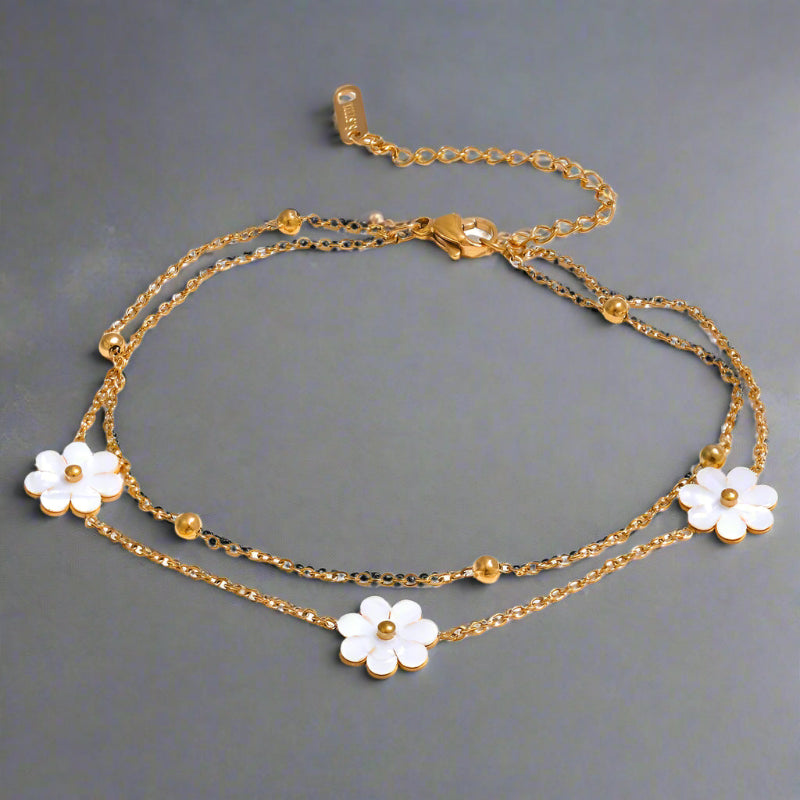 A collection of gold-colored necklaces and anklets with white daisy pendants.