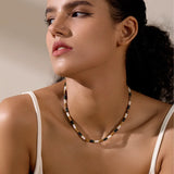  Close-up side view of woman wearing earth-tone shell beaded necklace with coastal style
