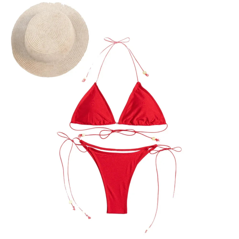 Flat lay of red lace-up string bikini set with matching straw beach hat.