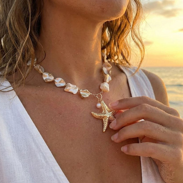 Woman wearing a starfish necklace with a sunset in the background