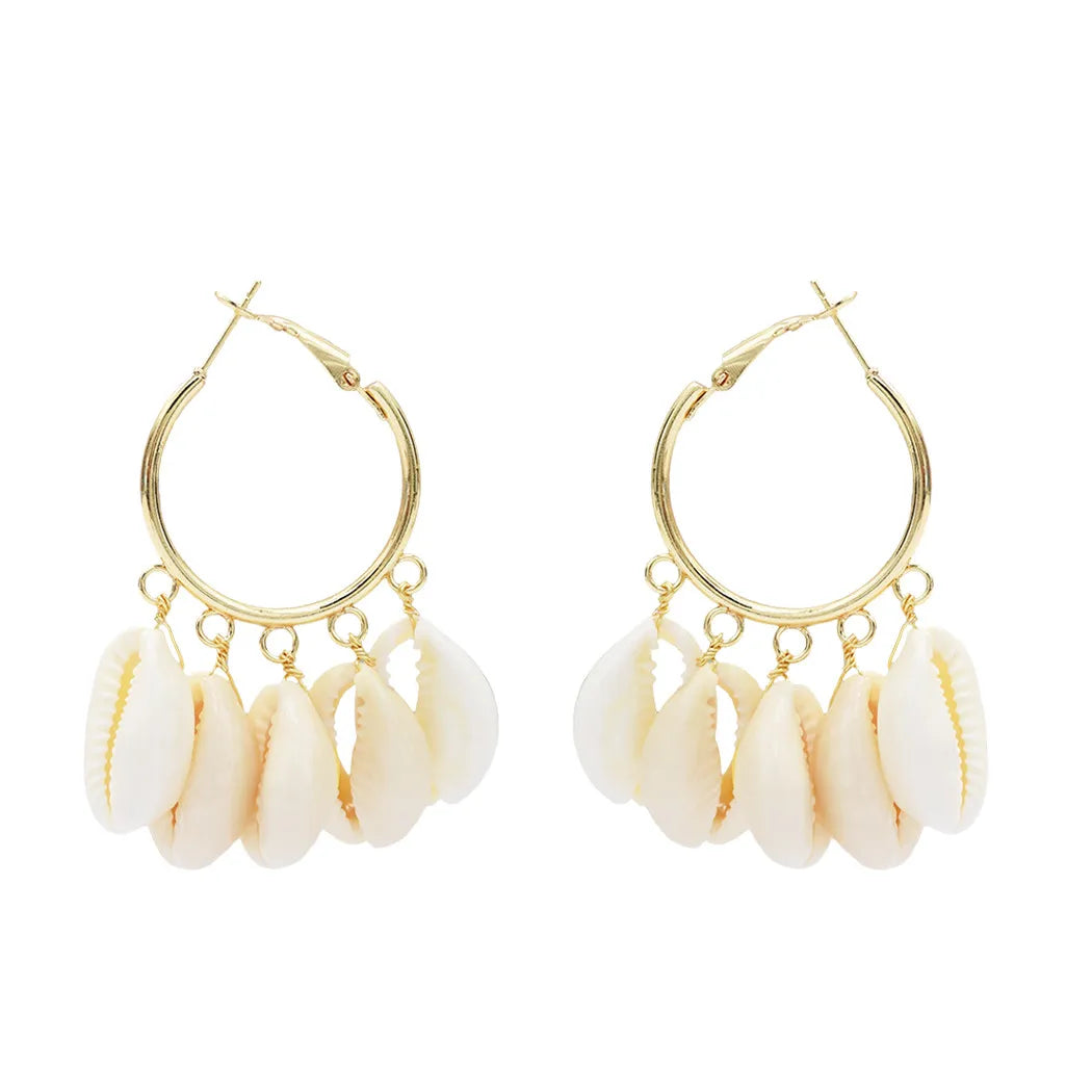 Gold cowrie hoop earrings with shell beads on a white background