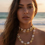 Woman wearing a cowrie choker necklace on a beach, boho chic style