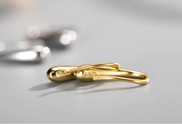 Gold infinity-shaped ring with '925' stamp on a gray background