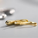 Gold infinity-shaped ring with '925' stamp on a gray background