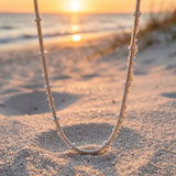 Sterling silver Necklace on sand with sunset in the background