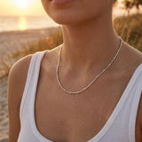 Woman wearing a sterling silver necklace on a beach at sunset