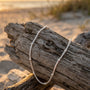 Driftwood with a necklace on a beach at sunset, featuring the brand 'Shell Vibe'.