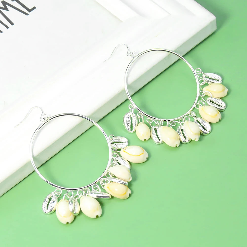 Pair of hoop earrings with shell decorations on a green surface