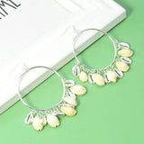 Pair of hoop earrings with shell decorations on a green surface