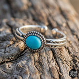 Sterling silver ring with a turquoise stone on a wooden surface, featuring the brand 'Shellvibe'.