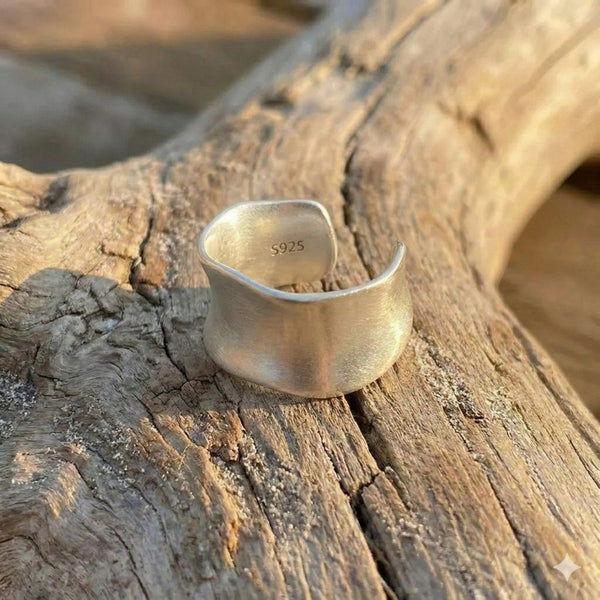Close-up of 925 sterling silver wide band ring on organic drift wood
