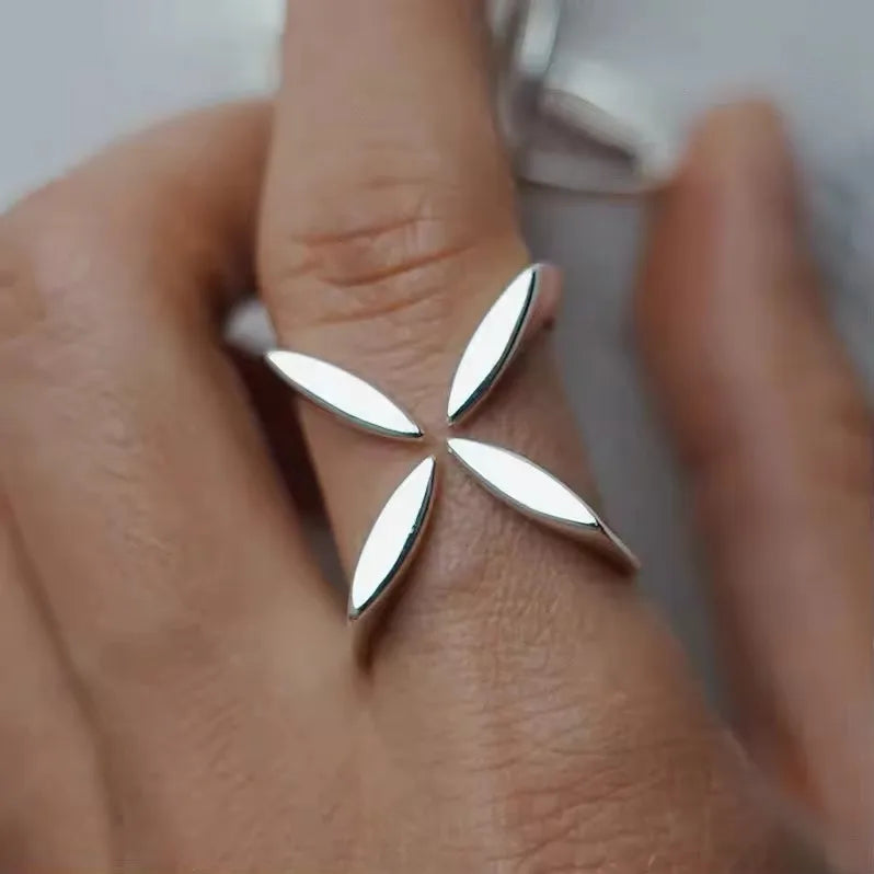 Silver floral ring on a person's finger with a neutral background