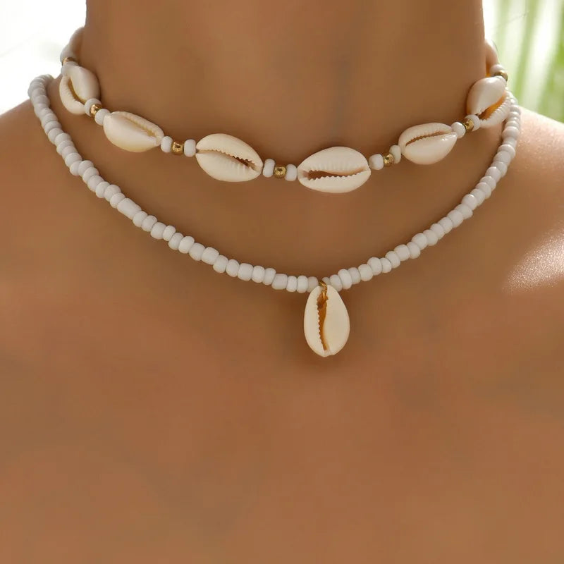 Necklace with cowrie shell and bead details on a blurred background