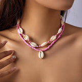 Necklace with pink beads and cowrie shell pendants on a woman's neck
