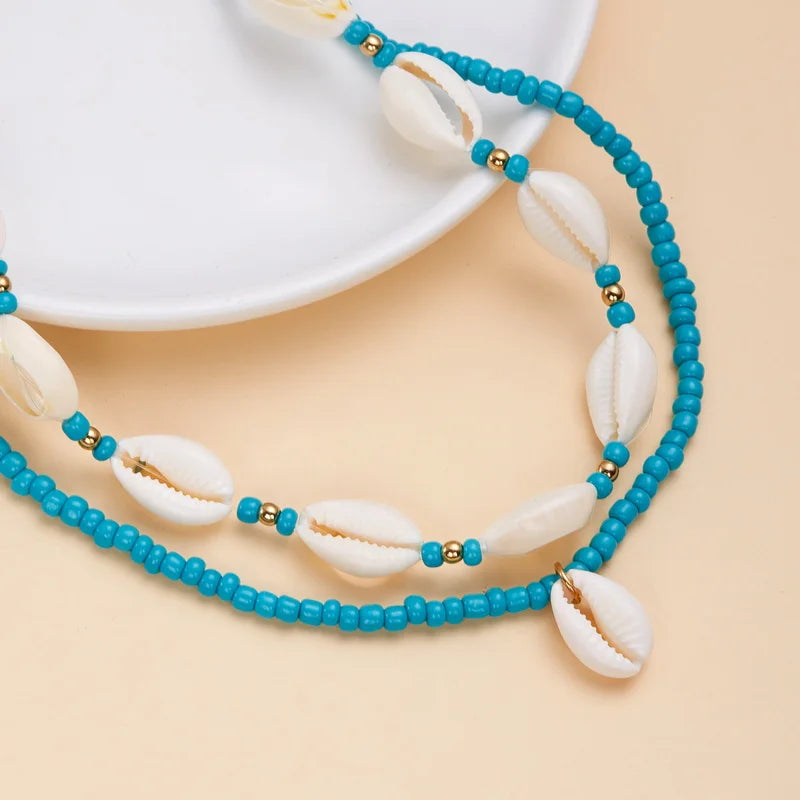 Necklace with blue beads and cowrie shells on a beige background