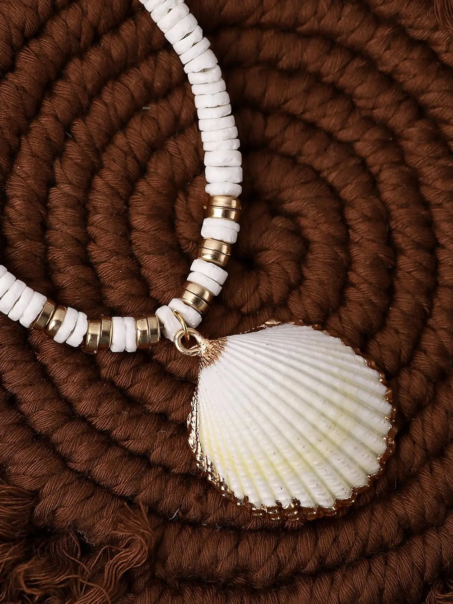 white shell on beaded necklace on brown textured surface