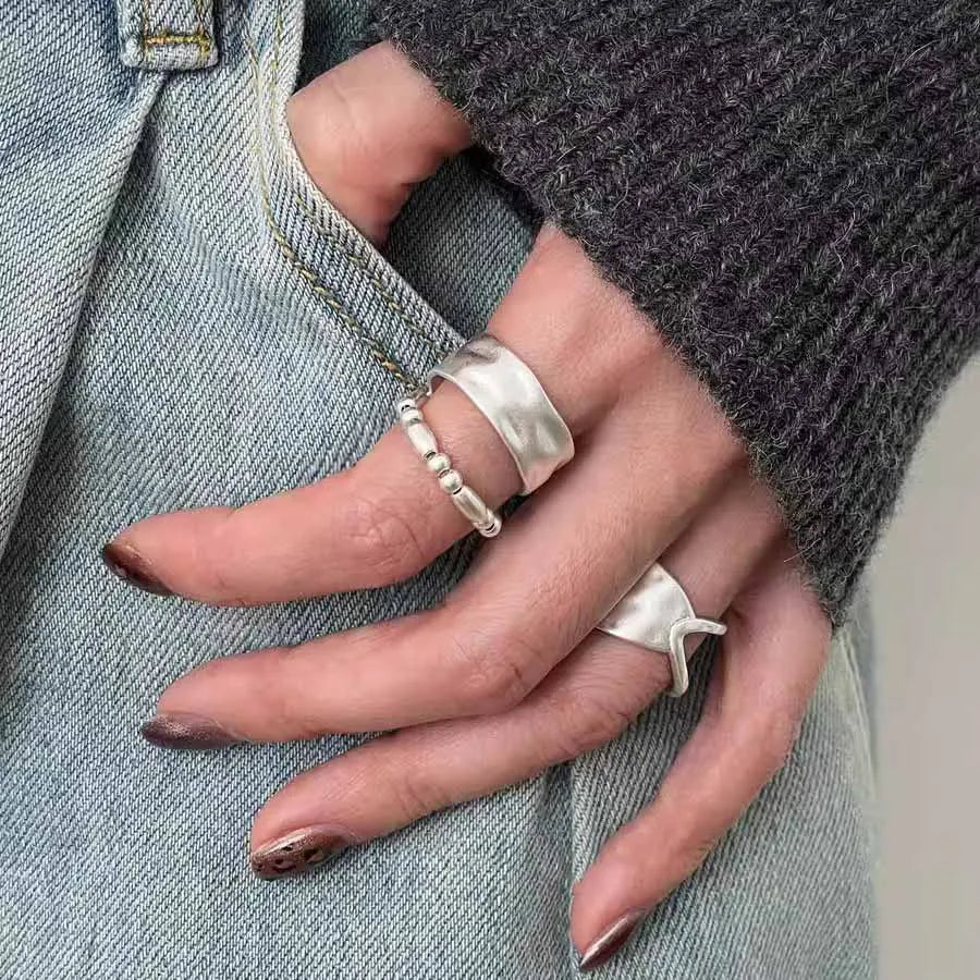 Woman wearing stacked silver rings on hand, featuring the Ocean Ripple ring and beaded accessories in a lifestyle setting.