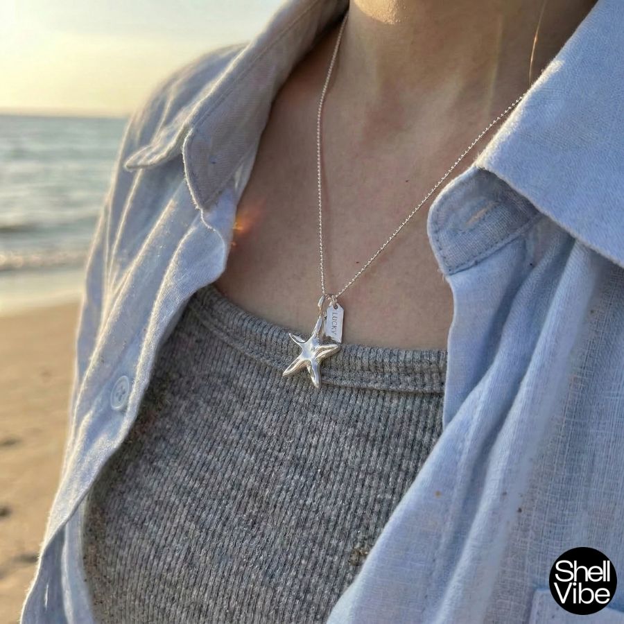 Person wearing a Sterling silver starfish necklace on a beach