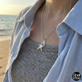 Person wearing a Sterling silver starfish necklace on a beach