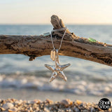 Sterling silver Starfish pendant necklace on a piece of driftwood with a beach background