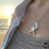 Sterling silver starfish pendant necklace on a person with a beach sunset background