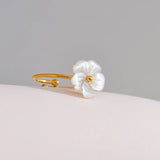 Gold ring with a white flower-shaped mother of pearl  on a light gray background