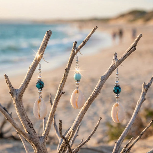 Cowrie Shell and bead earrings hanging from branches on a beach